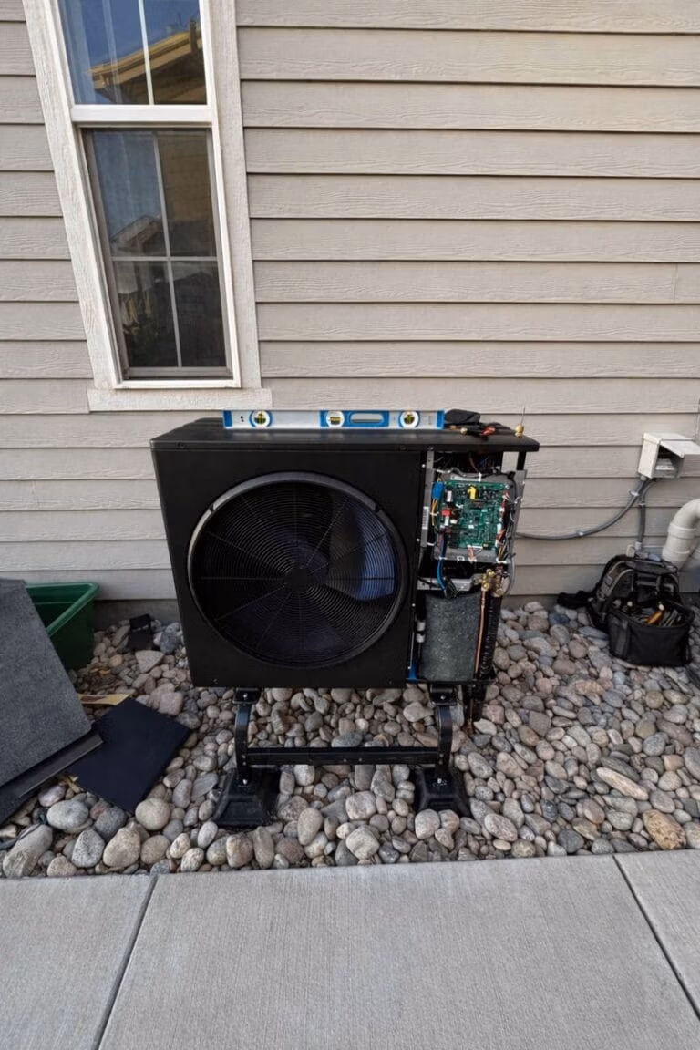 Outdoor cooling system condenser with service panel open beside a home